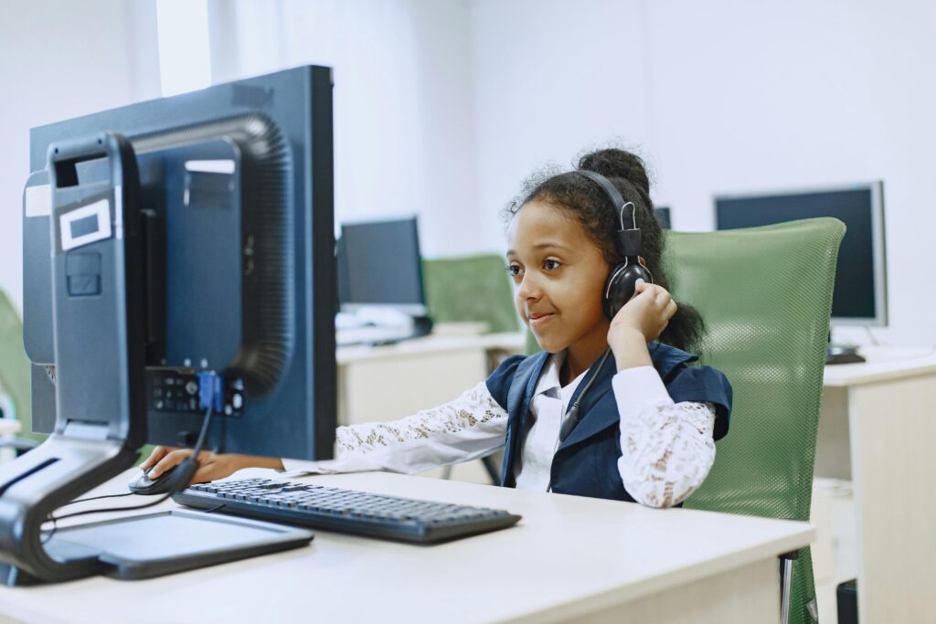 Smiling girl using computer in a modern lab setting, wearing a headset.